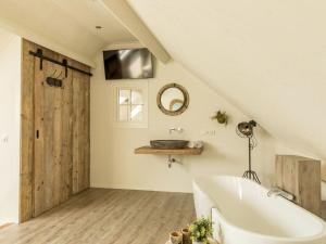 een badkamer met een wit bad en een wastafel bij Chill Op Ameland in Ballum