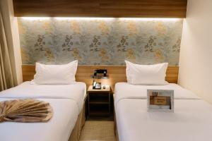 duas camas num quarto de hotel com lençóis brancos em L' Meridian Suite em Zamboanga