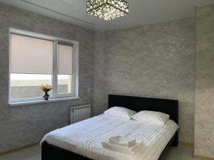 Schlafzimmer mit einem Bett mit weißer Bettwäsche und einem Fenster in der Unterkunft Двухкомнатная квартира в элитном ЖК Оазис с видом на МОРЕ! in Aqtau