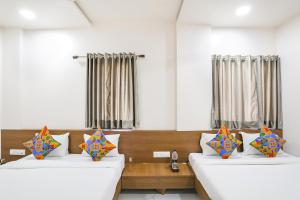Habitación con 2 camas y almohadas coloridas. en Hotel D Grand, en Shirdi