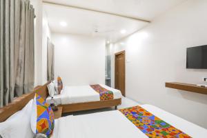 a hotel room with two beds and a television at Hotel D Grand in Shirdi