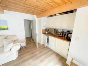 a kitchen with white cabinets and a white couch in a room at Ferienwohnung Dat seute Huus EG klein in Maasholm +4 photos
