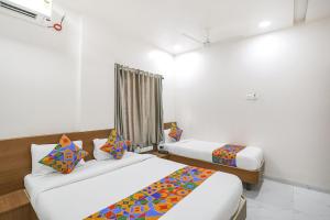 a hotel room with two beds and a window at Hotel D Grand in Shirdi