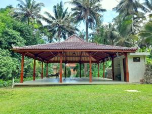 a pavilion in a field with palm trees in the background at As I Am Ubud Retreat in Ubud