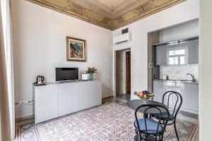 a kitchen with white cabinets and a table and chairs at Hotel La Residenza in Messina