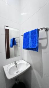 a white bathroom with a sink and a mirror at Hens Guesthouse Syariah in Gadobangkong +8 photos