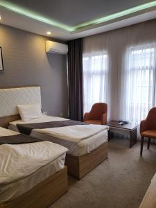 a hotel room with two beds and two chairs at Baku ZamZam Hotel in Baku