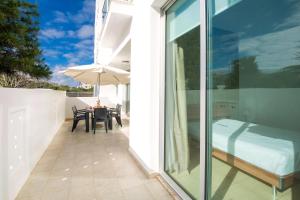 een balkon met een bed en een tafel met een parasol bij Calypso - Coralli Beachfront Apartment in Protaras