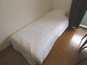 AO Dazaifu / Vacation STAY 61720 في Chikushino: سرير أبيض في غرفة ذات أرضية خشبية