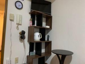 a shelf with a phone and a table and a clock at AO Dazaifu / Vacation STAY 61720 in Chikushino