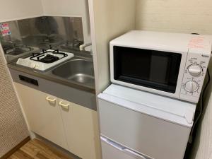 eine kleine Küche mit Mikrowelle und Spüle in der Unterkunft AO Dazaifu - Vacation STAY 93787 in Chikushino