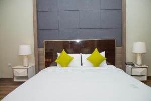 a bedroom with a large white bed with yellow pillows at Savan Resorts in Savannakhet