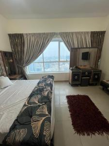 a bedroom with a bed and a tv and a window at 22 R1 Luxury Master Room in a 4-bedroom apartment with attached washroom and fantastic city view ### 22 R1 غرفة ماستر فاخرة في شقة مكونة من 4 غرف نوم مع حمام ملحق وإطلالة رائعة على المدينة ### in Ajman 