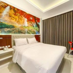 a bedroom with a white bed and a painting at Solo Grand City in Lawean