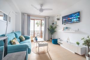 a living room with a blue couch and a tv at PRIMERA LINEA Playa Romana Frontal al Mar ALBERT VILLAS in Alcossebre