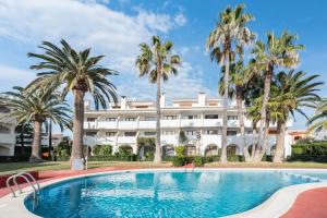 a hotel with a swimming pool and palm trees at PRIMERA LINEA Playa Romana Frontal al Mar ALBERT VILLAS in Alcossebre