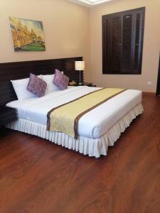 a bedroom with a large bed with a wooden floor at Savan Resorts in Savannakhet