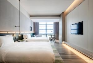 a hotel room with two beds and a flat screen tv at 深圳英威斯顿酒店 Investon Hotel Shenzhen in Lung Wa