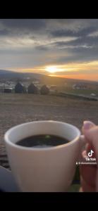a person holding a cup of coffee with the sunset in the background at Panorama Świętokrzyska in Górno