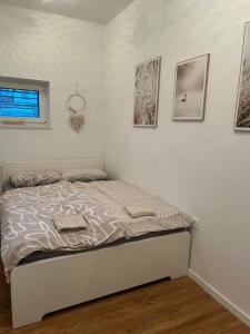 Cama en habitación blanca con cuadros en la pared en Apartma Naty en Liubliana
