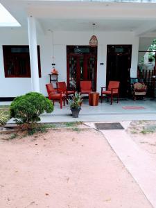 a porch with red chairs on a white house at Area 51 Apartment in Mirissa
