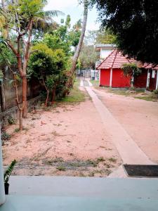 a dirt road with a red building and trees at Area 51 Apartment in Mirissa