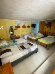 a room with four beds and a tv in it at Hotel Pueblito Playa in Cartagena de Indias