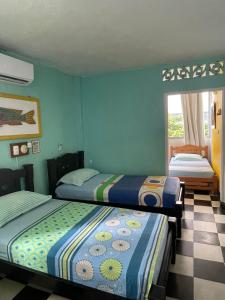 2 camas en una habitación con paredes verdes en Hotel Pueblito Playa, en Cartagena de Indias
