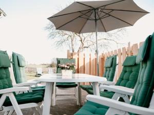 a white table and chairs with an umbrella at Holiday home Zum Nagel in Pommerby