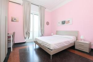 a bedroom with pink walls and a bed with a desk at SAN MARTINO HOUSE in Genova