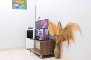 Soka Guesthouse Syariah في Martapura: غرفة بها تلفزيون و مزهرية مع نبات