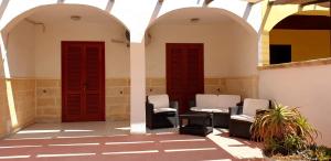 zwei rote Türen und zwei Stühle auf einer Terrasse in der Unterkunft trilocale chianca by salentolimit in Porto Cesareo
