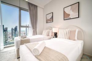 2 weiße Betten in einem Zimmer mit einem großen Fenster in der Unterkunft Magnificent 3BR apartment with Assistant Rm at Downtown Views II T2 Downtown Dubai by Deluxe Holiday Homes in Dubai