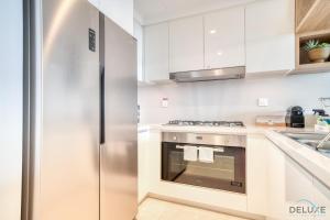 eine weiße Küche mit einem Kühlschrank aus Edelstahl in der Unterkunft Magnificent 3BR apartment with Assistant Rm at Downtown Views II T2 Downtown Dubai by Deluxe Holiday Homes in Dubai
