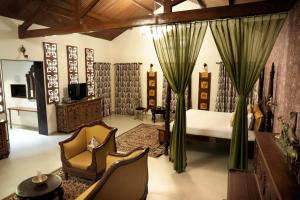 Heritage Khirasara Palace في راجكوت: غرفة نوم بسرير وكرسي وتلفزيون