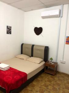 een slaapkamer met een bed met een hart aan de muur bij Alia Express CZ Hotel in Pasir Puteh