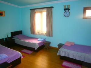 Habitación con 2 camas y reloj en la pared en Aygestan Comfort Holiday Home, en Ereván