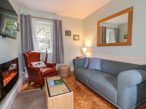 a living room with a blue couch and a mirror at Knoll Cottage in Bakewell