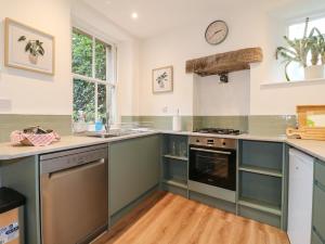 a kitchen with blue cabinets and a clock on the wall at Knoll Cottage in Bakewell +12 photos