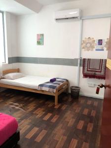 een slaapkamer met een bed en een houten vloer bij Alia Express CZ Hotel in Pasir Puteh