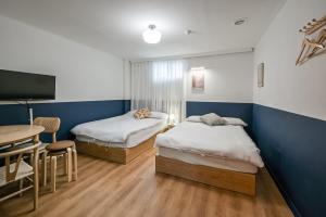 two beds in a room with a table and a tv at SSH Myeongdong Dongdo Hostel in Seoul
