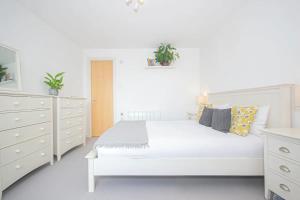 een witte slaapkamer met een groot wit bed en een dressoir bij Renovu Exclusive Rooms London in Londen