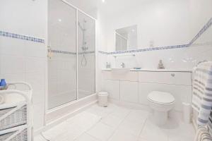 een witte badkamer met een douche en een toilet bij Renovu Exclusive Rooms London in Londen
