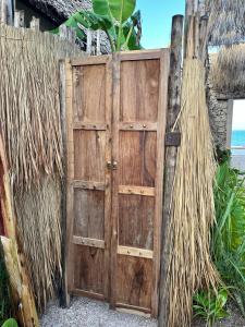 eine offene Holztür mit einem Zaun und dem Meer in der Unterkunft Be Zanzibar Boutique Hotel in Mfumbwi