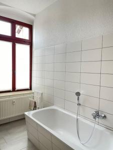 ein weißes Bad mit einer Badewanne und einem Fenster in der Unterkunft Moderne und stilvolle Wohnung direkt am Teich in Altenburg