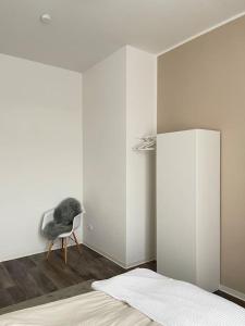 a bedroom with a bed and a chair in a room at Moderne und stilvolle Wohnung direkt am Teich in Altenburg