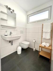 a white bathroom with a sink and a toilet at Aparthotel Peerless Dine in Heidenheim an der Brenz