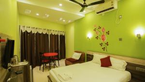 - une chambre avec un lit, une chaise et une table dans l'établissement Hotel Shantinivas, à Tarapith