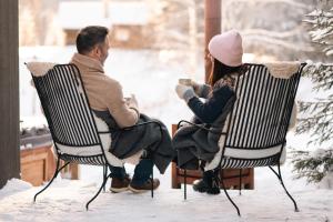 mężczyzna i kobieta siedzący na krzesłach w śniegu w obiekcie Ådalsvollen retreat w mieście Verdal