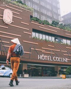 Un uomo che cammina davanti a un hotel di Hôtel Colline a Da Lat